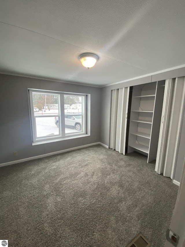 unfurnished bedroom with dark colored carpet and a textured ceiling