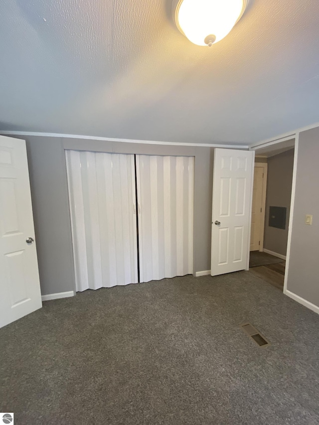 unfurnished bedroom with dark colored carpet and a textured ceiling