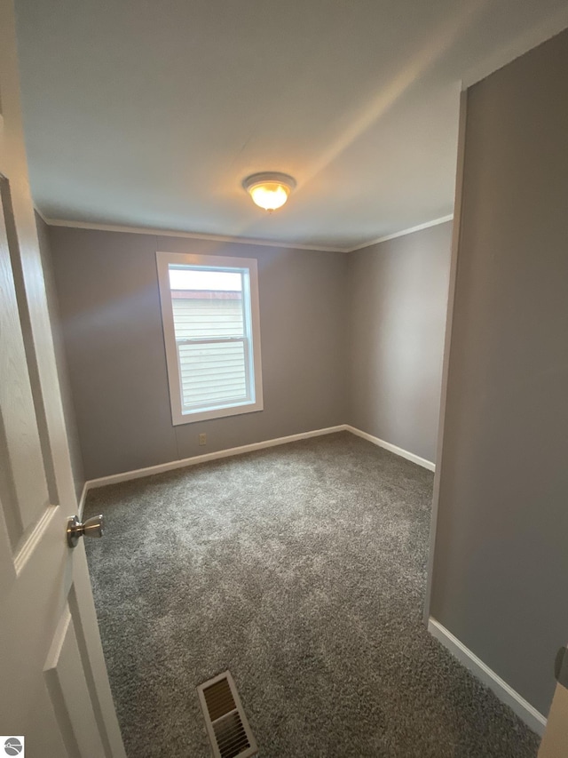 empty room featuring crown molding and dark carpet