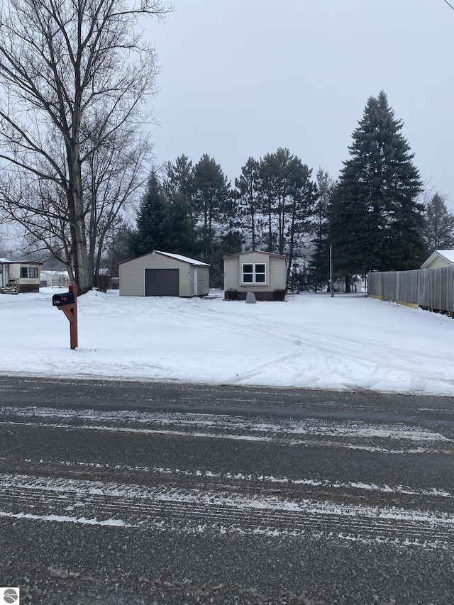 snowy yard with a garage and an outdoor structure