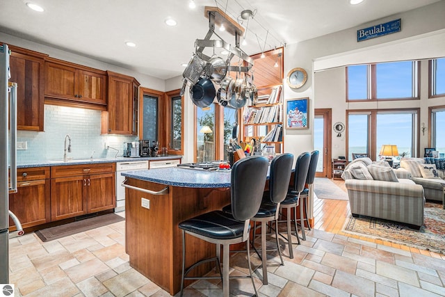 kitchen with a center island, white dishwasher, sink, decorative backsplash, and light wood-type flooring