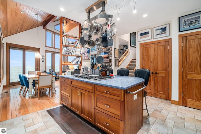 kitchen with a kitchen island, light hardwood / wood-style floors, decorative light fixtures, a breakfast bar, and a water view