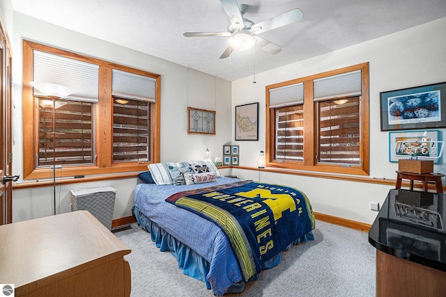 carpeted bedroom with ceiling fan and a textured ceiling