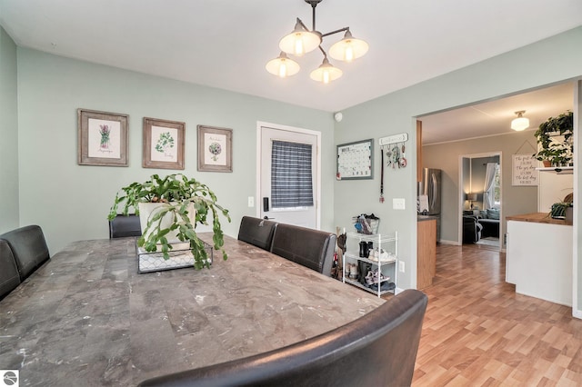 dining area with light hardwood / wood-style floors and an inviting chandelier