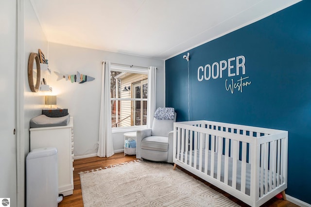 bedroom with a crib and hardwood / wood-style floors