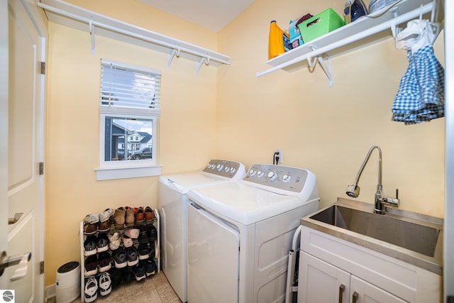 clothes washing area with washing machine and clothes dryer, sink, and cabinets