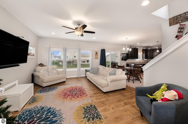 living room with wood-type flooring, ceiling fan with notable chandelier, and sink