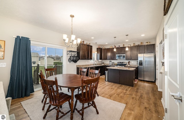 dining space with a notable chandelier, sink, and light hardwood / wood-style flooring