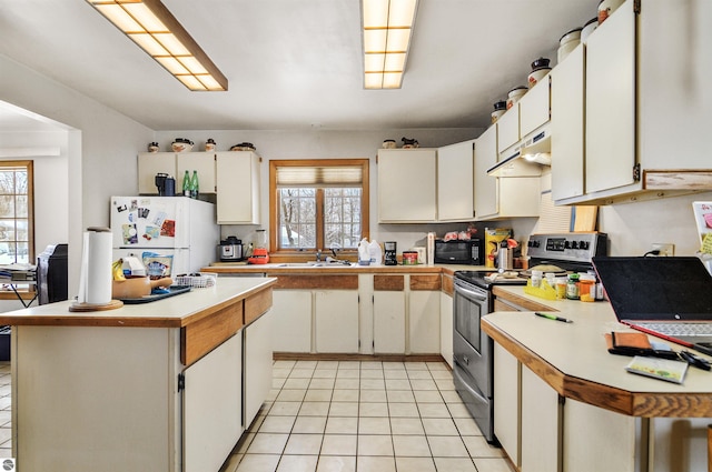 kitchen featuring stainless steel electric range oven, white cabinets, a healthy amount of sunlight, and white refrigerator