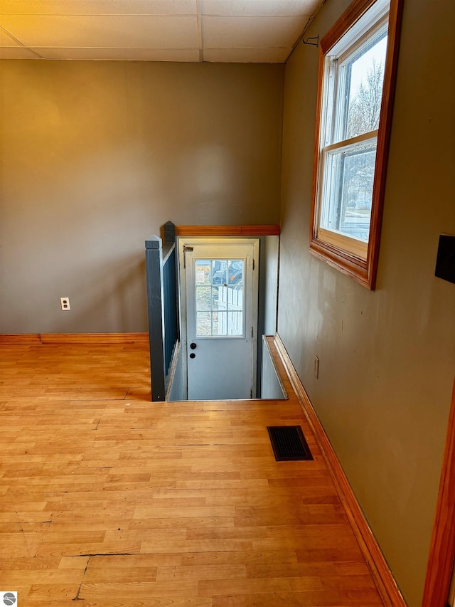 doorway to outside featuring a paneled ceiling, light hardwood / wood-style floors, and plenty of natural light