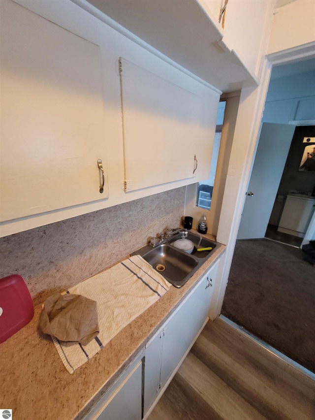 kitchen with white cabinetry, wood-type flooring, and sink