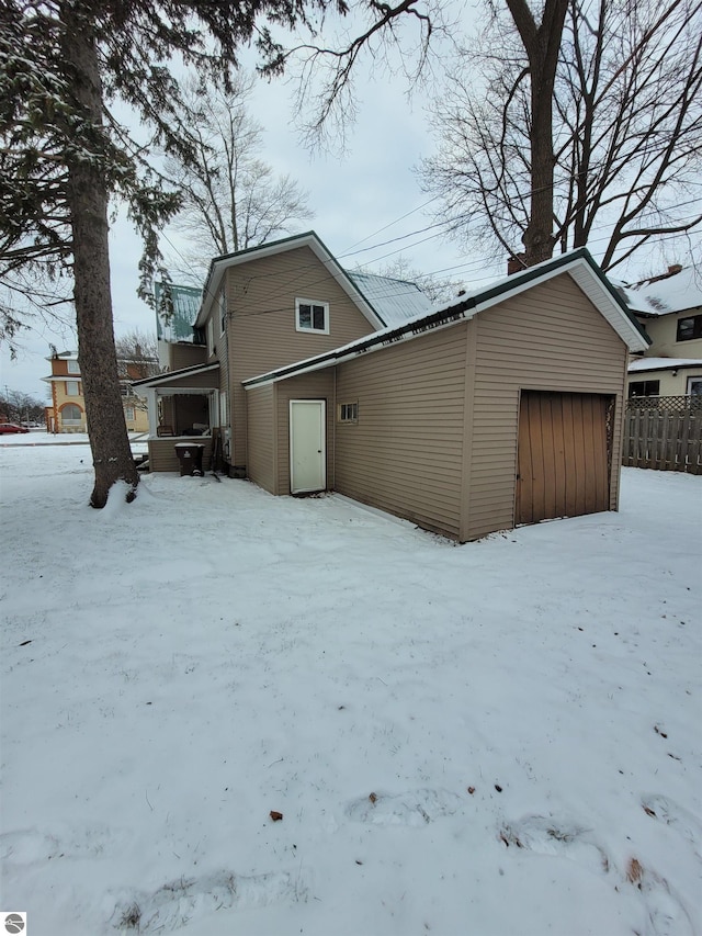 snow covered back of property with a garage