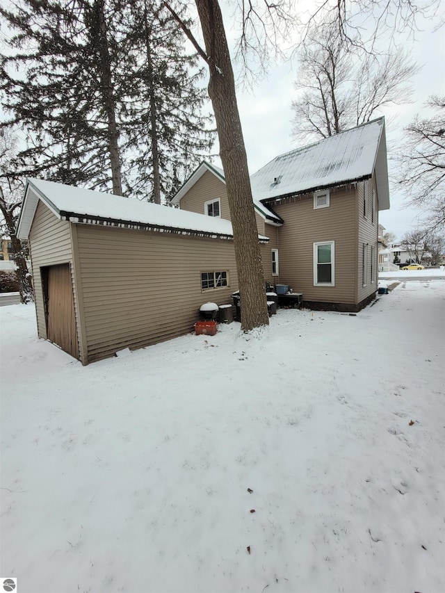 snow covered back of property with a garage