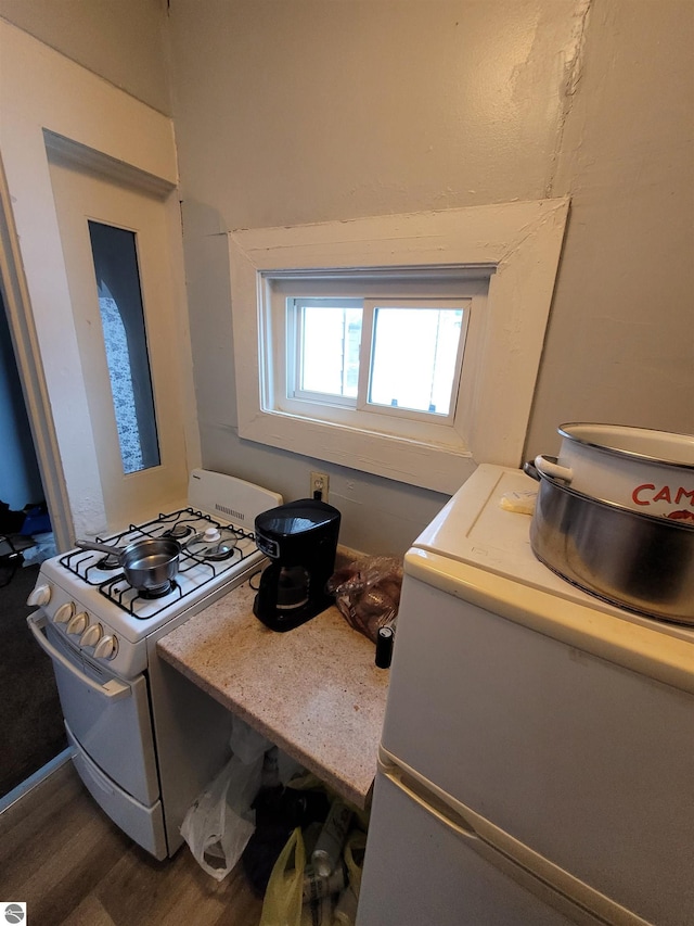 kitchen with wood-type flooring, refrigerator, and white gas stove