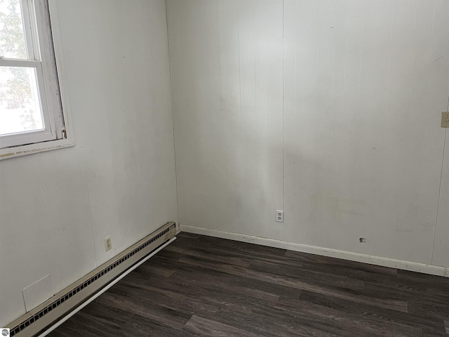 empty room with dark hardwood / wood-style flooring and a baseboard radiator