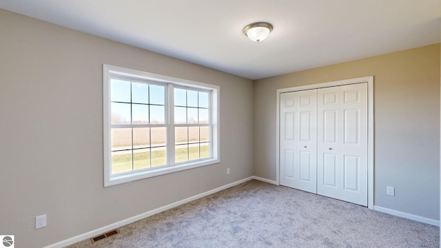 unfurnished bedroom featuring light carpet and a closet