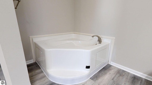 bathroom with a bath and hardwood / wood-style flooring