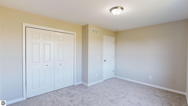 unfurnished bedroom with light carpet and a closet