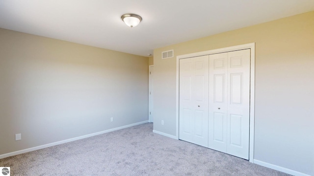 unfurnished bedroom with light colored carpet and a closet