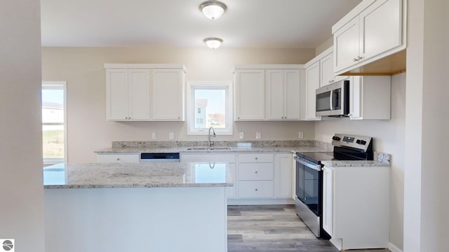 kitchen with light stone countertops, appliances with stainless steel finishes, light wood-type flooring, sink, and white cabinetry