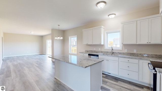 kitchen with sink, a kitchen island, stainless steel dishwasher, decorative light fixtures, and white cabinets