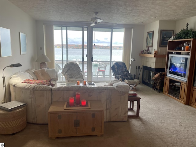 living room featuring carpet flooring, a wealth of natural light, ceiling fan, and a fireplace