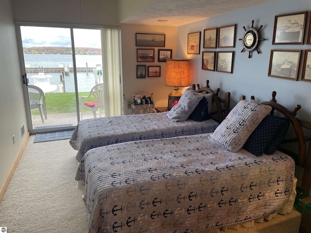 bedroom with access to outside, carpet floors, a water view, and a textured ceiling