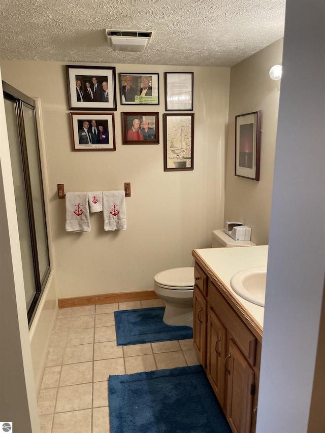 full bathroom featuring enclosed tub / shower combo, tile patterned floors, a textured ceiling, toilet, and vanity