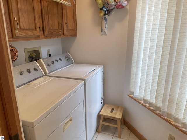 clothes washing area featuring cabinets, light tile patterned floors, and washer and dryer