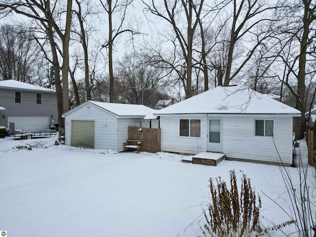 snow covered property featuring a garage and an outdoor structure