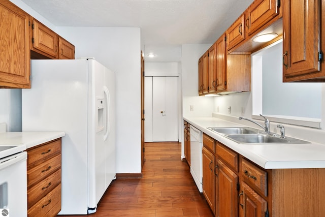 kitchen featuring white appliances, sink, and dark wood-type flooring