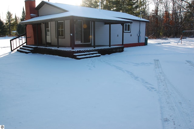 snow covered rear of property with covered porch