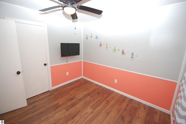 unfurnished bedroom featuring hardwood / wood-style flooring, ceiling fan, and wood walls