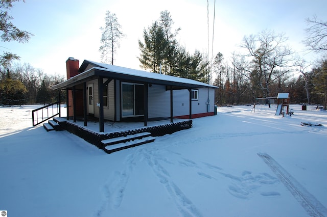 snow covered property with covered porch