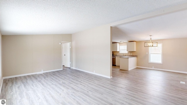 unfurnished living room with light hardwood / wood-style floors, sink, and a textured ceiling