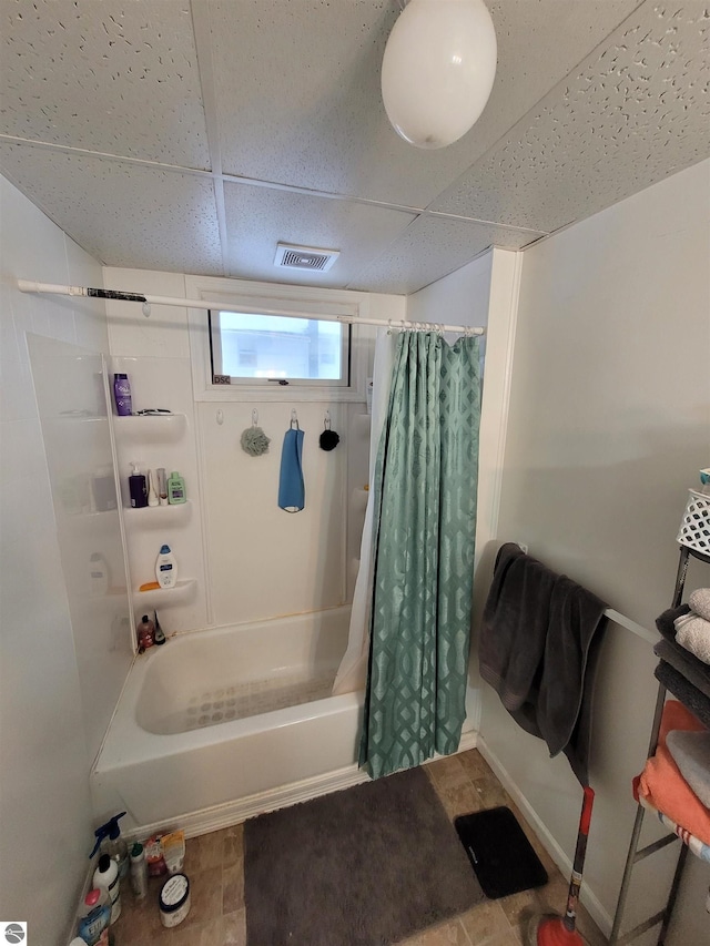 bathroom with a paneled ceiling and shower / bath combination with curtain