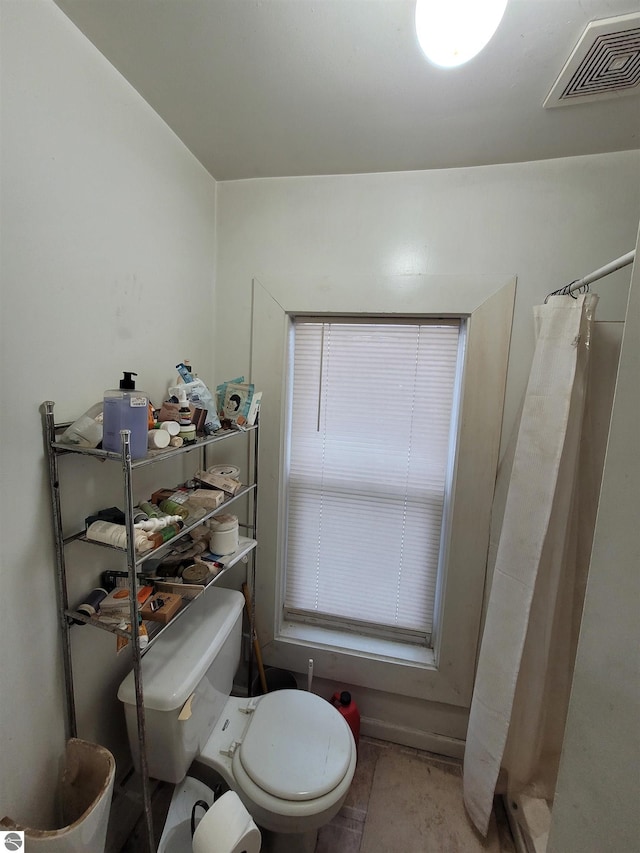 bathroom featuring toilet and curtained shower