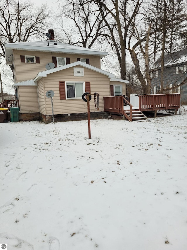 snow covered back of property featuring a deck