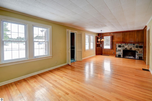 unfurnished living room featuring light wood-type flooring, a healthy amount of sunlight, crown molding, and a fireplace