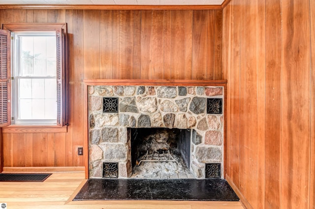 details featuring ornamental molding, wood walls, and a stone fireplace