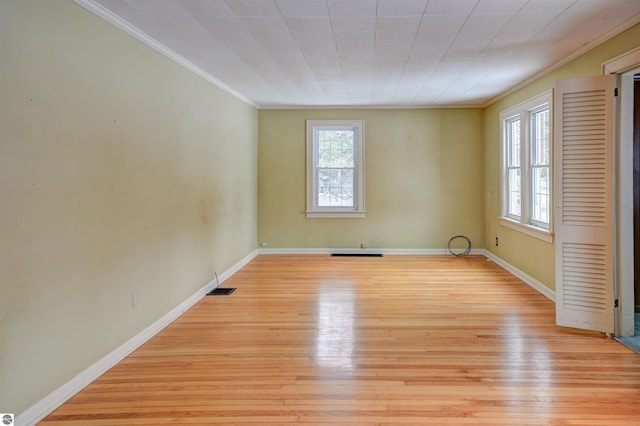 empty room featuring ornamental molding and light wood-type flooring