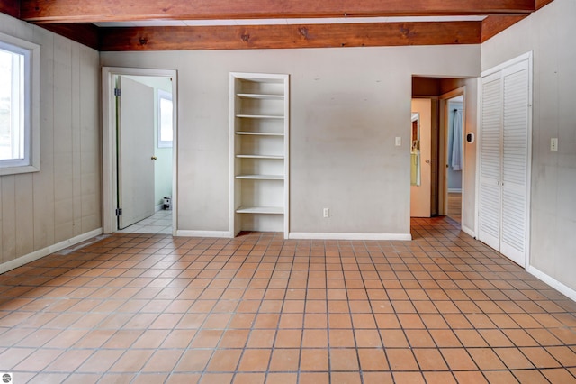 spare room featuring light tile patterned floors, built in features, and beam ceiling