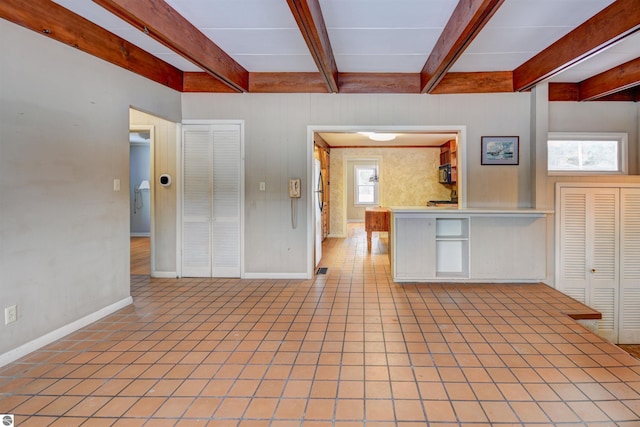 kitchen with beam ceiling, plenty of natural light, and stainless steel fridge