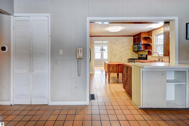 kitchen featuring sink, wooden walls, and stainless steel appliances