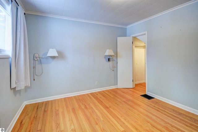 spare room featuring crown molding and light hardwood / wood-style floors