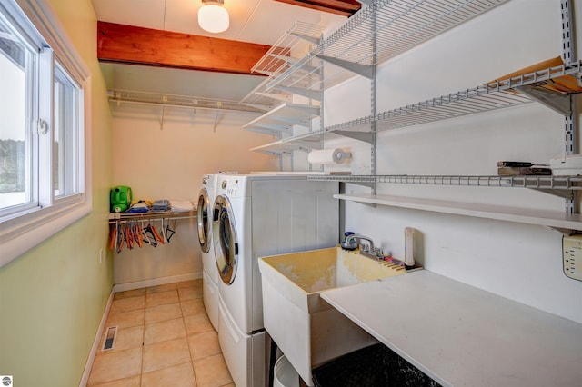 clothes washing area featuring washing machine and dryer and light tile patterned flooring