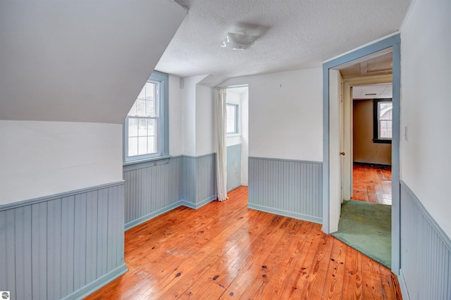 bonus room featuring a textured ceiling, lofted ceiling, and light wood-type flooring