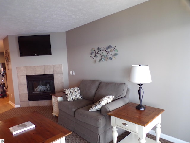 living room featuring a tile fireplace and a textured ceiling