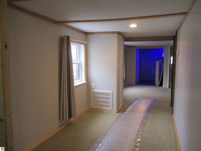 hall with crown molding and light carpet