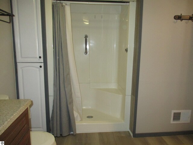 bathroom featuring vanity, hardwood / wood-style flooring, toilet, and curtained shower